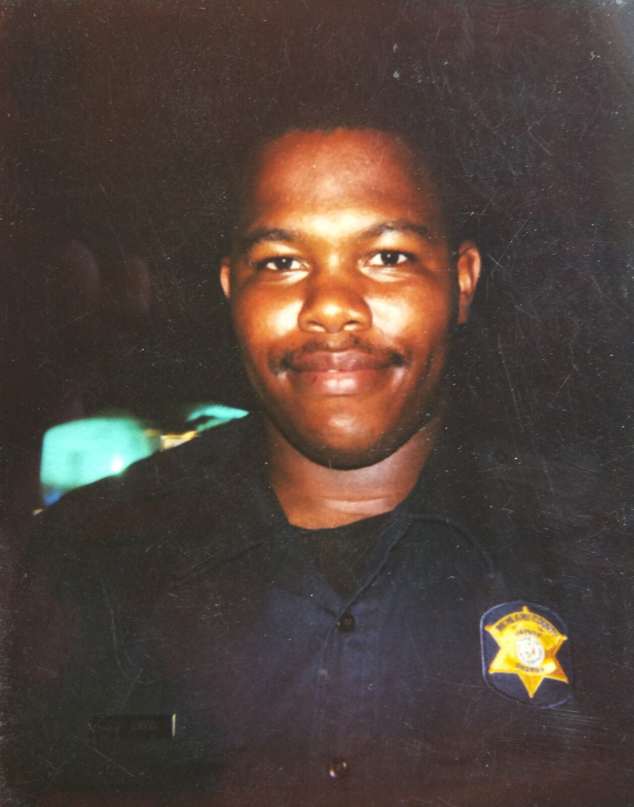 Chris Davios as a young deputy in his sheriff's department uniform with badge
